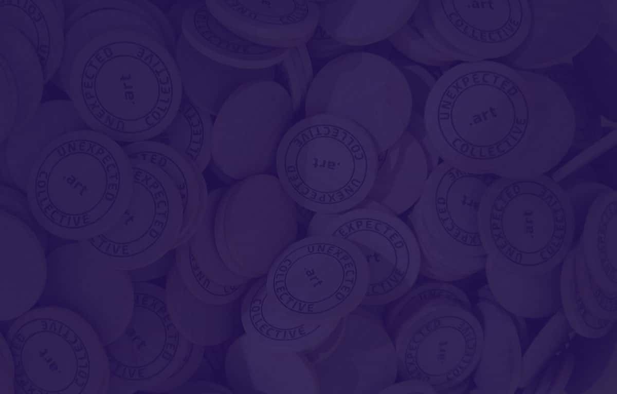 Looking into a bucket full of wooden nickels that are printed with 'Unexpected Collective .art'.